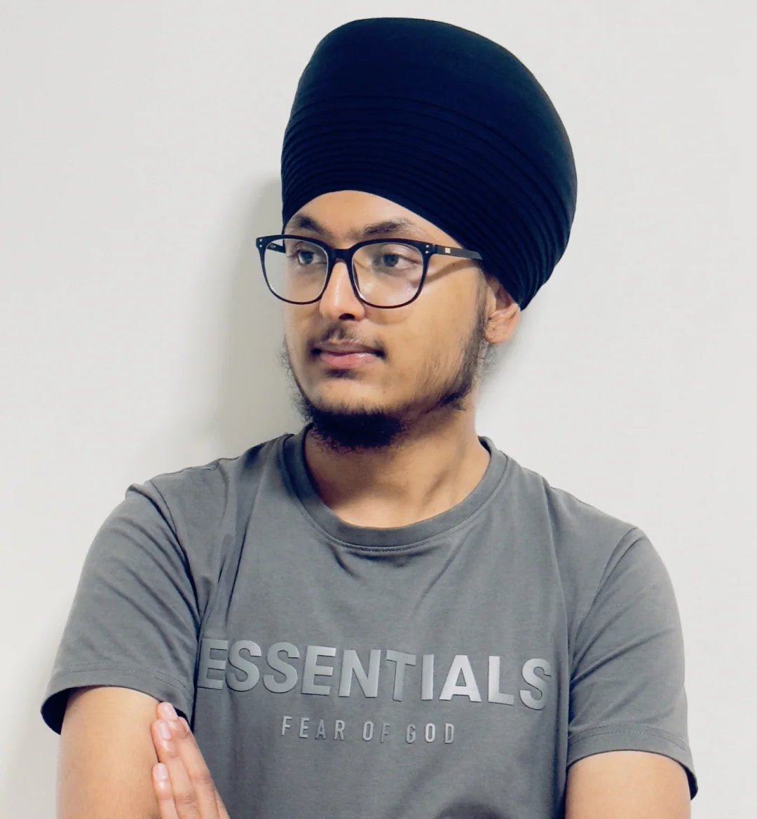 Jajwinder Singh in a grey T-shirt against a light wall, looking toward the words