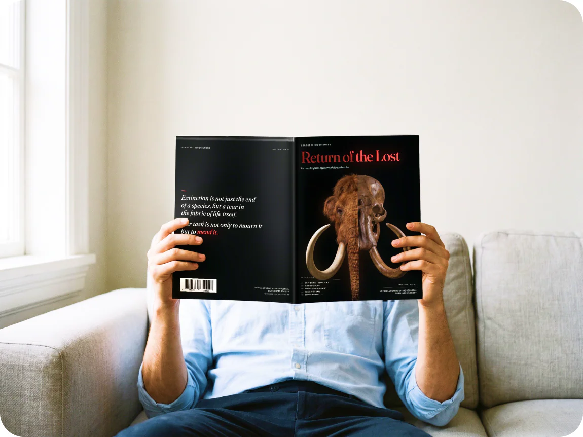 A person on a sofa holds the open magazine up in front of their face.